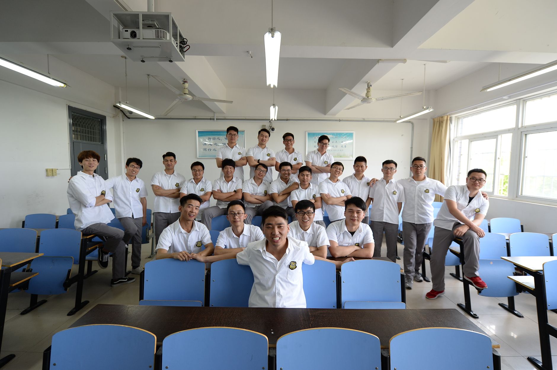 一群穿白衬衫的年轻男子在教室内合影